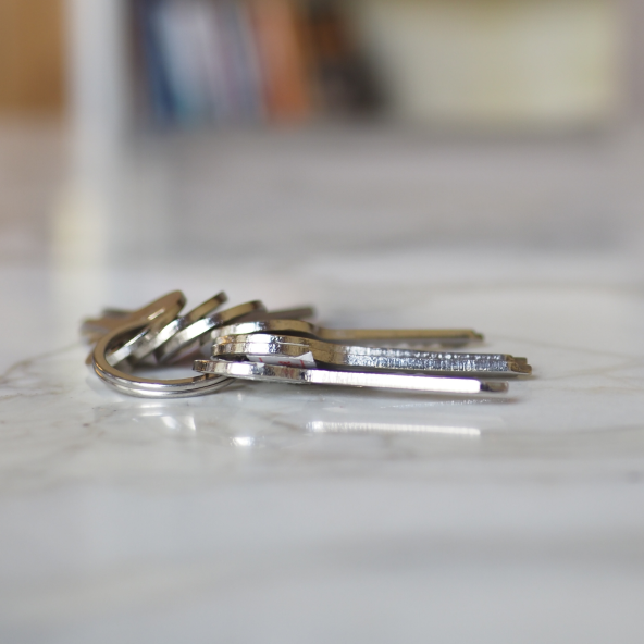 kilka srebrnych kluczy leżących na białym blacie symbolizujących biuro rzeczy znalezionych