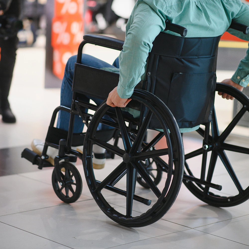 Osoba poruszająca się na wózku inwalidzkim w centrum handlowym, symbolizująca dostępność i mobilność osób niepełnosprawnych