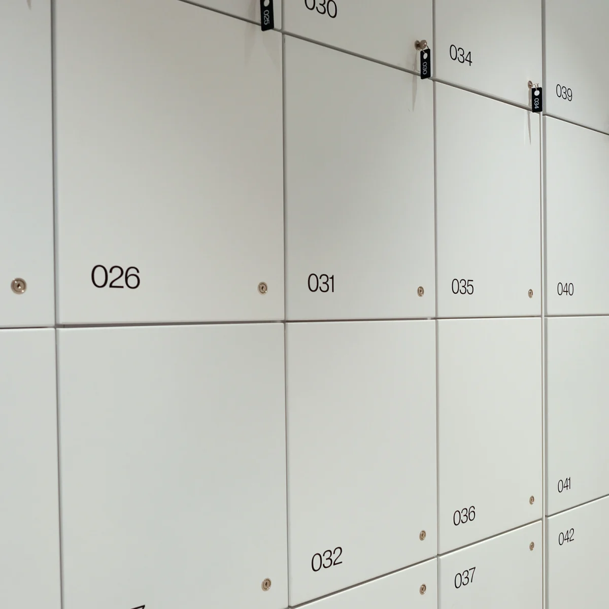 Rząd białych skrytek depozytowych z numerami na drzwiczkach