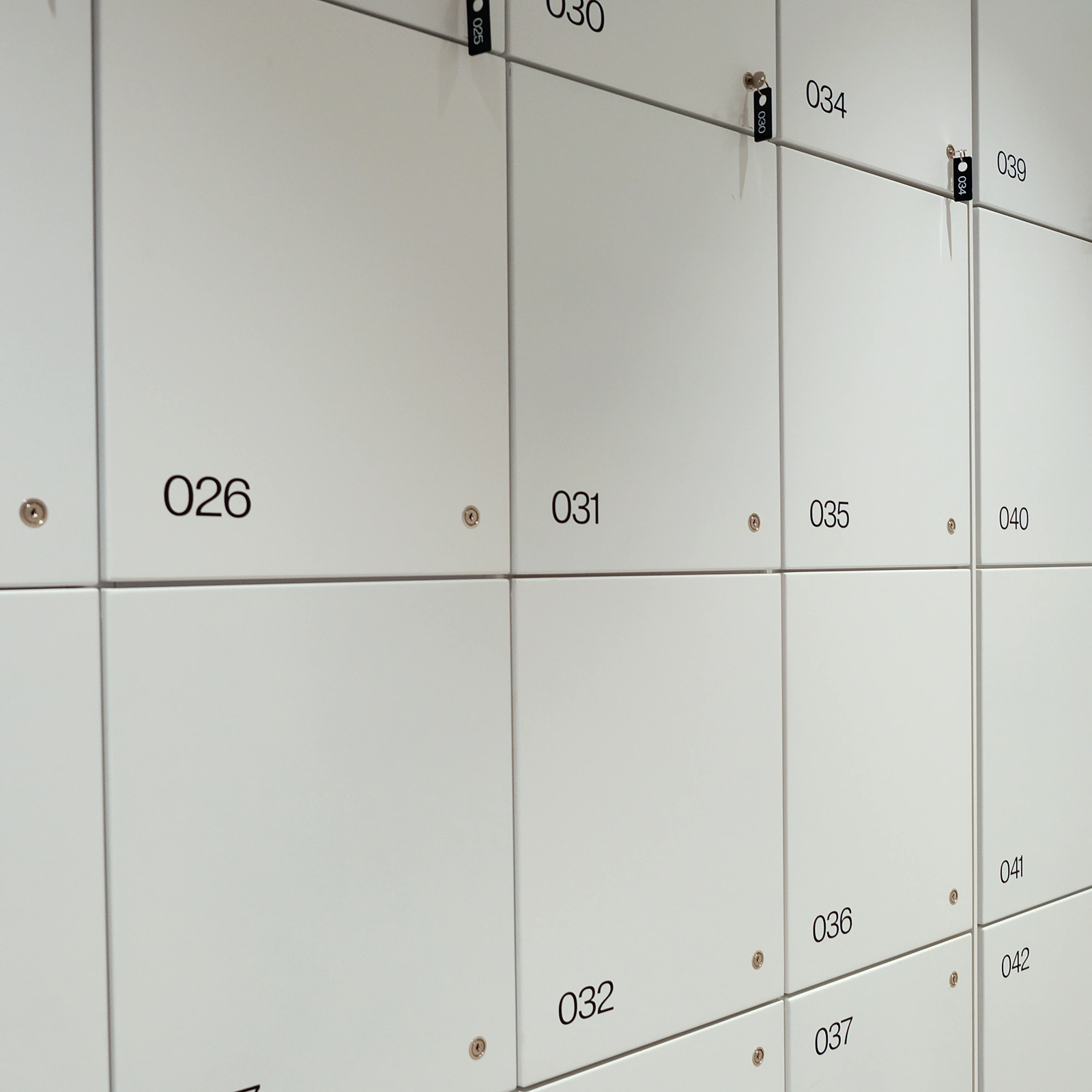 Rząd białych skrytek depozytowych z numerami na drzwiczkach