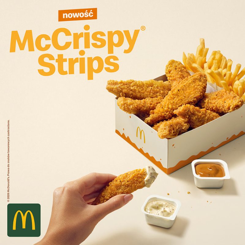 Grafika reklamowa McDonald’s przedstawia nowość McCrispy Strips – panierowane stripsy z kurczaka podawane z frytkami i sosami. Na zdjęciu widoczna jest także dłoń trzymająca kawałek kurczaka zanurzony w sosie. Całość utrzymana jest w jasnej, apetycznej stylistyce.