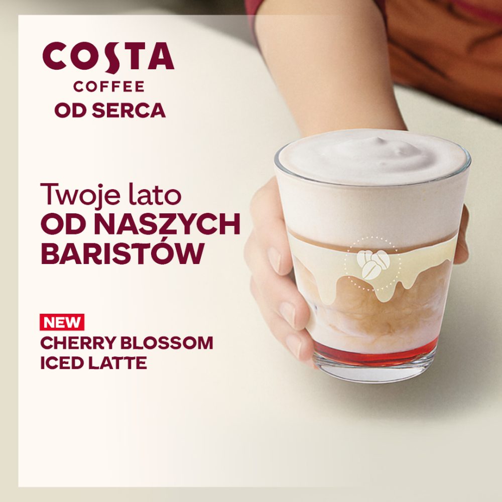 Grafika promocyjna Costa Coffee przedstawia dłoń trzymającą szklankę mrożonego napoju kawowego z mleczną pianką i wiśniowym syropem na dnie. Na grafice widoczne są napisy „Twoje lato od naszych baristów” oraz „New Cherry Blossom Iced Latte”. W lewym górnym rogu znajduje się logo Costa Coffee z hasłem „Od serca”.