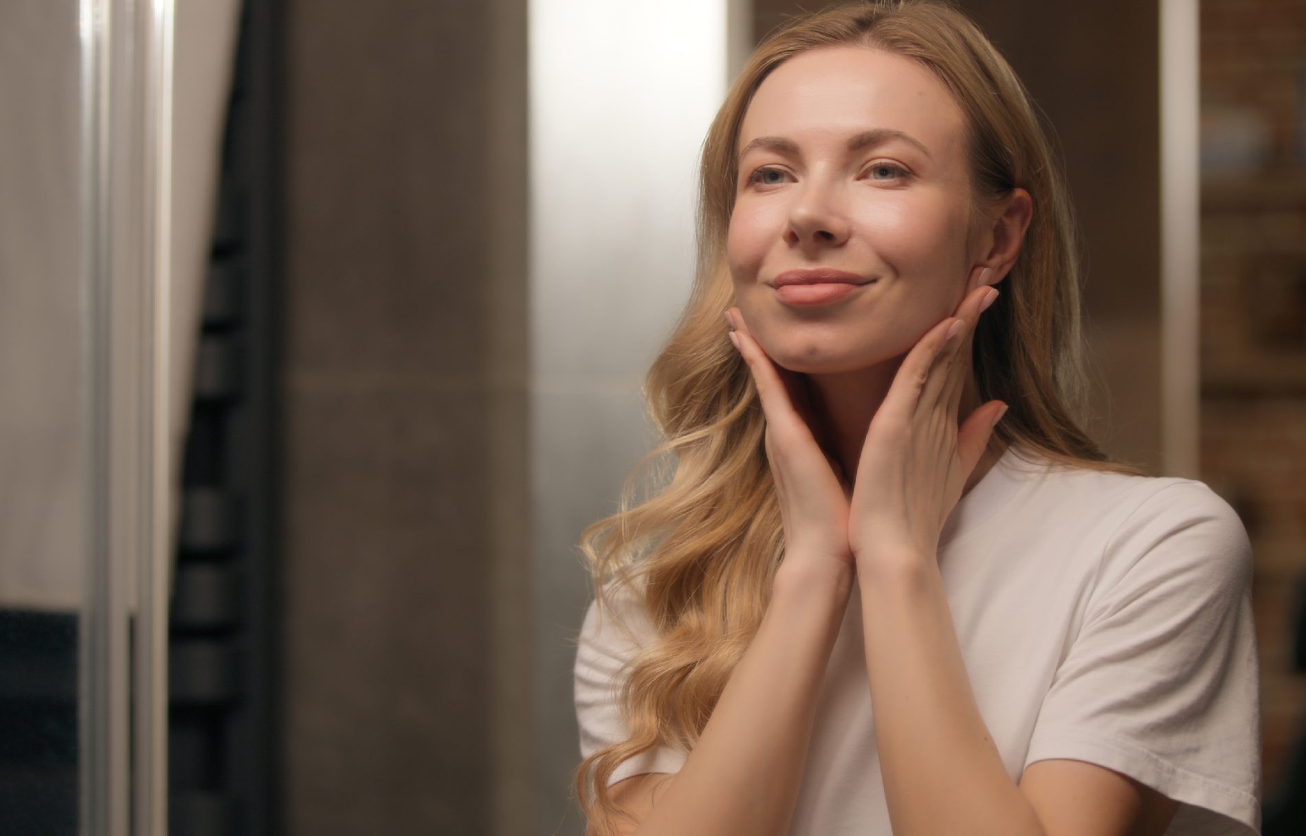 Kampania wizerunkowa w M1 dotycząca marek związanych z kosmetykami i beauty. Zrelaksowana kobieta smarująca twarz kremem, przed lustrem.